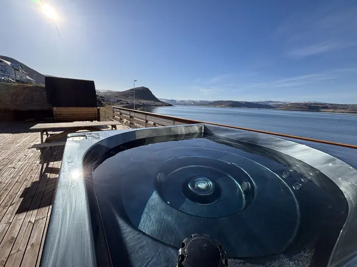 The hot tub on the deck with the fjord behind it